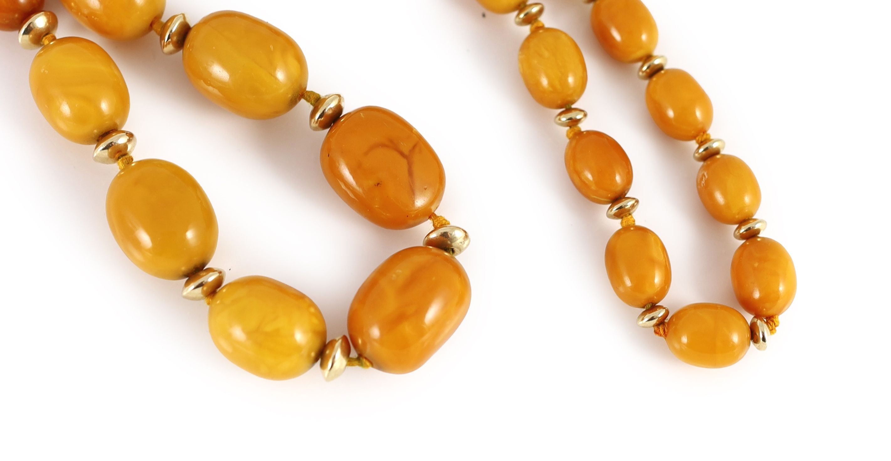 A single strand graduated oval amber bead necklace, with gilt metal spacers, 80cm, gross weight 92 grams.